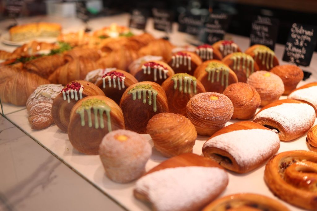Assorted bakery pastries with drizzles and powdered sugar on display. Tempting fresh variety.